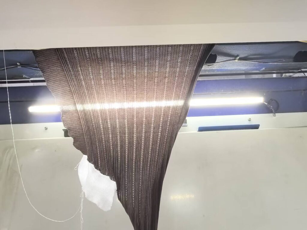 Computer flat knitting machine producing sweater panels, knitwear factory production